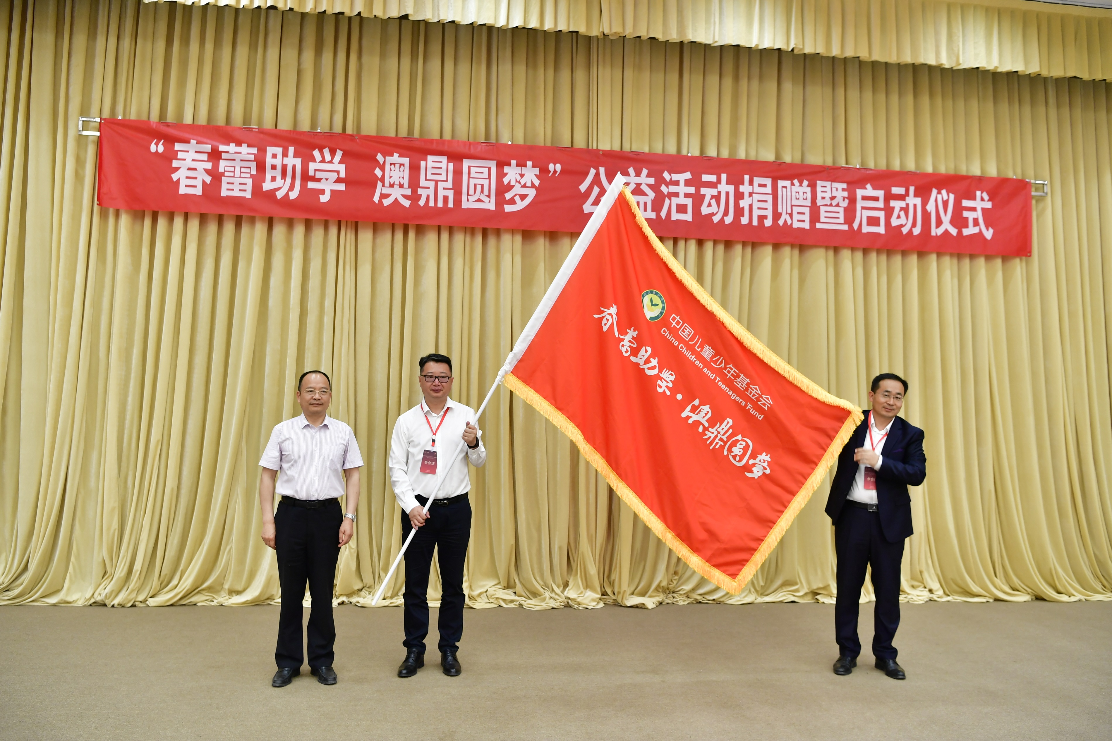 6.中国儿童少年基金会副理事长、秘书长朱锡生将印制“春蕾助学 澳鼎圆梦”的红色旗帜授给青岛澳鼎生物科技有限公司，象征2021年“春蕾助学 澳鼎圆梦”公益活动正式启动.JPG